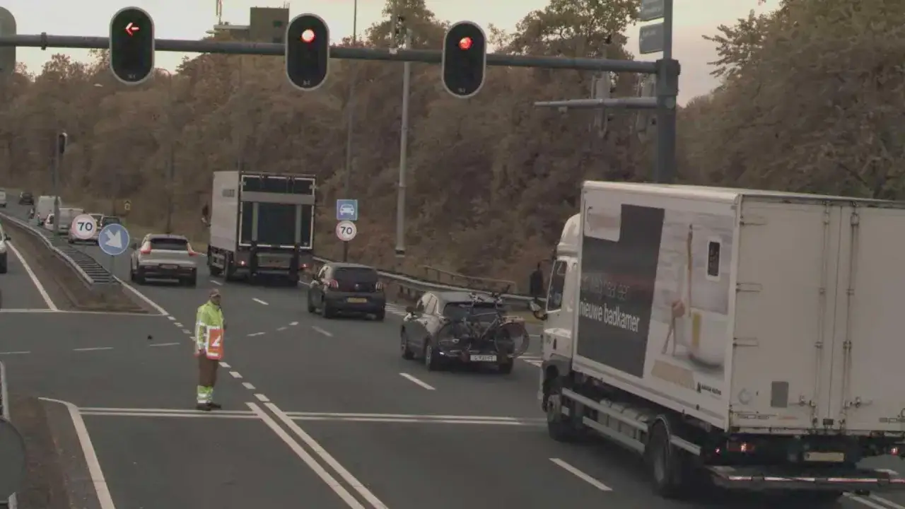 Verkeersregelaar bij rood licht, auto's wachten. Een vrachtwagen met reclame voor een nieuwe badkamer rijdt door.