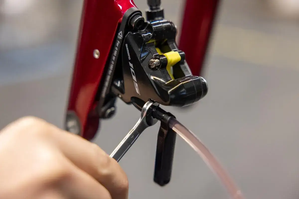 Hand vult hydraulische remmen fiets bij met een sleutel en slang.