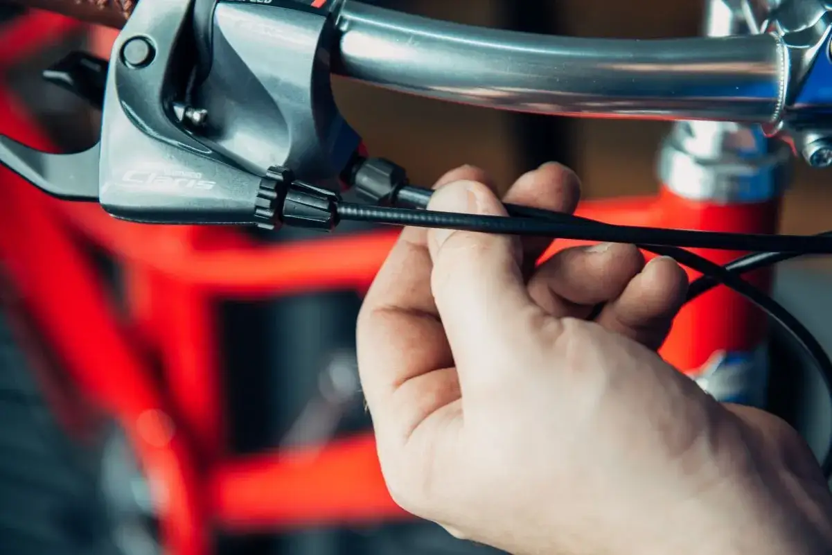 Hand bevestigt een nieuwe versnellingskabel fiets vervangen aan de Shimano Claris shifter.