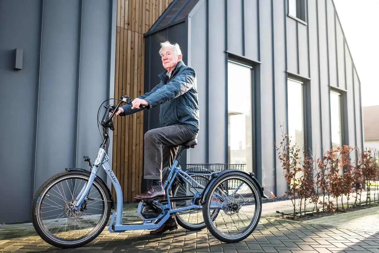 Oudere man geniet van een rit op een driewieler, een veilige fiets voor ouderen, voor een moderne woning.