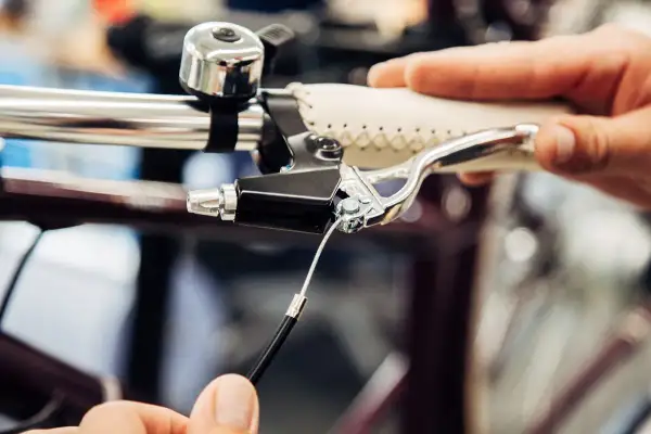 Hand replacing a bicycle's remkabel. Close-up of the brake lever and cable connection.