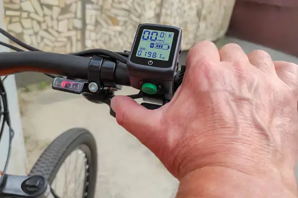 Hand op stuur van een elektrische fiets zonder trappen. Het display toont 00.0 km/u en 198.1 km.