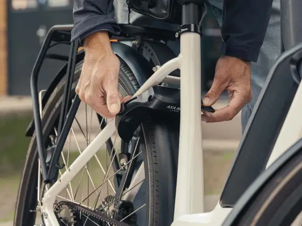 Een persoon bevestigt een ringslot aan een fiets. Dit type slot, wat is een ringslot, beschermt tegen diefstal door het achterwiel te blokkeren.