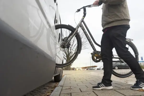 Man met fiets bij auto. Een diefstal preventie chip op de fiets zorgt voor extra veiligheid.