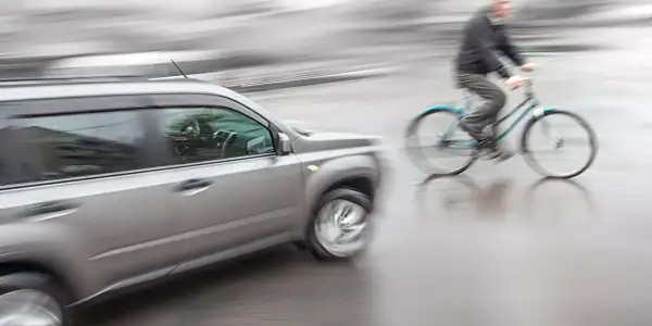 Een auto en fietser in beweging, mogelijk een situatie die leidt tot schadevergoeding fietsongeval.