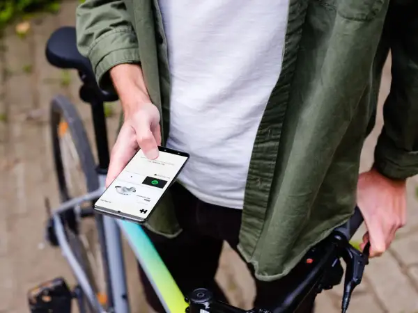 Man op fiets houdt smartphone vast, toont app voor communiceren tijdens fietsen.