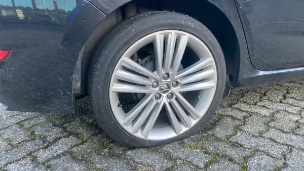 Een lekke band op de racefiets van de auto. De band is plat en de velg rust op de stenen ondergrond.