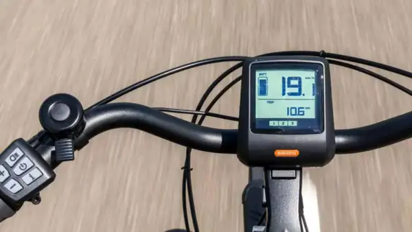 Close-up of an e-bike handlebar with a digital display showing speed and battery level.