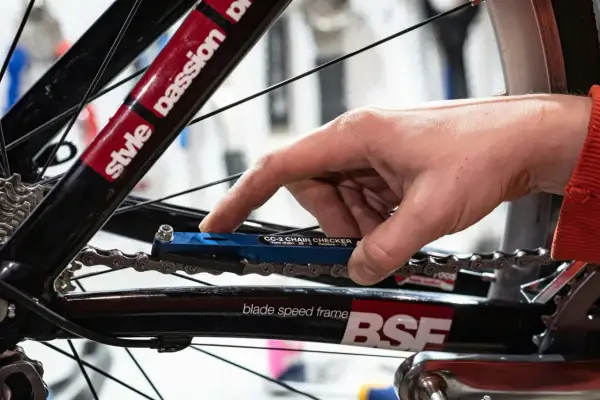 Hand gebruikt een blauwe kettingmeter om te controleren of het tandwiel van de fiets vervangen moet worden.
