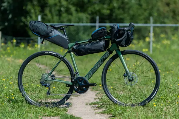 Groene Merida racefiets met bikepacking tassen, klaar voor een avontuurlijke tocht.