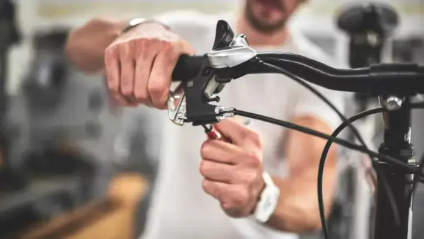 Man stelt de terugtraprem af met een sleutel aan het stuur van een fiets.