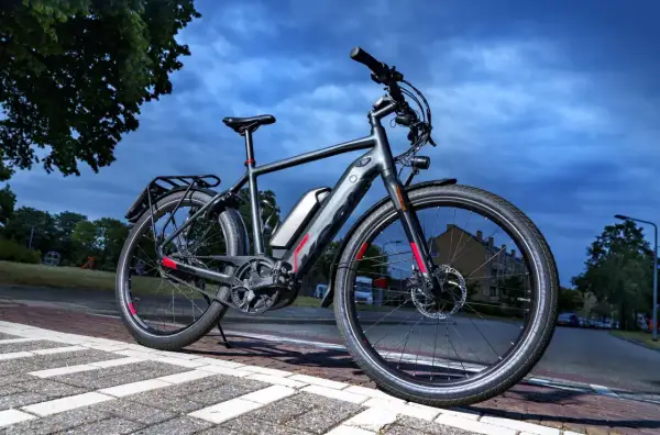 Grijze speed pedelec met bagagedrager en accu, klaar voor een rit. Het kenteken is niet zichtbaar, maar de fiets is wel voorzien van alle benodigde onderdelen.