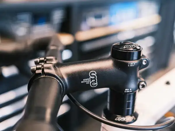 Zwarte fietsstuurpen, merk State Bicycle Co., met spacers om de stuurpen te verhogen voor een comfortabelere fietshouding.