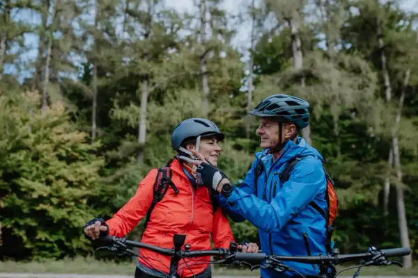 Een stel op mountainbikes, met fietshelm verplicht in Frankrijk, geniet van een bosrit.