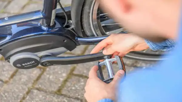 Handen draaien een trapper los van een e-bike met Bosch Active Line motor.