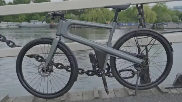 Moderne, hippe stadsfiets met een uniek frame, geparkeerd op een brug met uitzicht op boten.