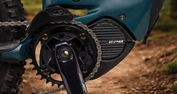 Close-up van een e-bike aandrijfsysteem met Shimano STEPS motor. De ketting loopt over de tandwielen en de motorbehuizing met EP8-logo.