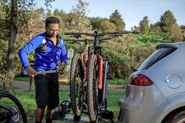 Man laadt fietsen op een fietsendrager achter een auto. Hopelijk is de fiets gestolen inboedelverzekering geregeld.
