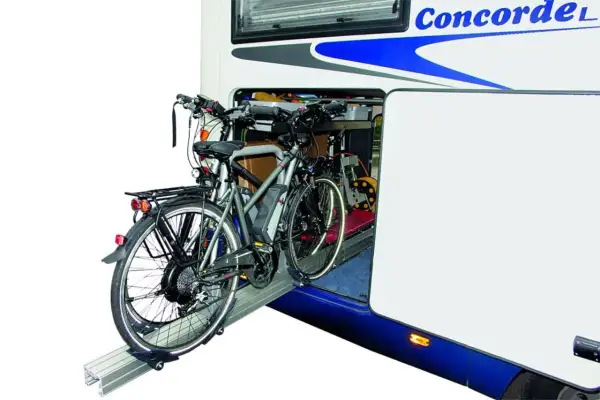 Twee elektrische fietsen staan klaar voor transport in de ruime schuur van een camper.