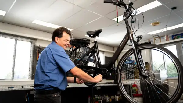 Man werkt aan een fiets, mogelijk om deze om te bouwen naar een driewieler.